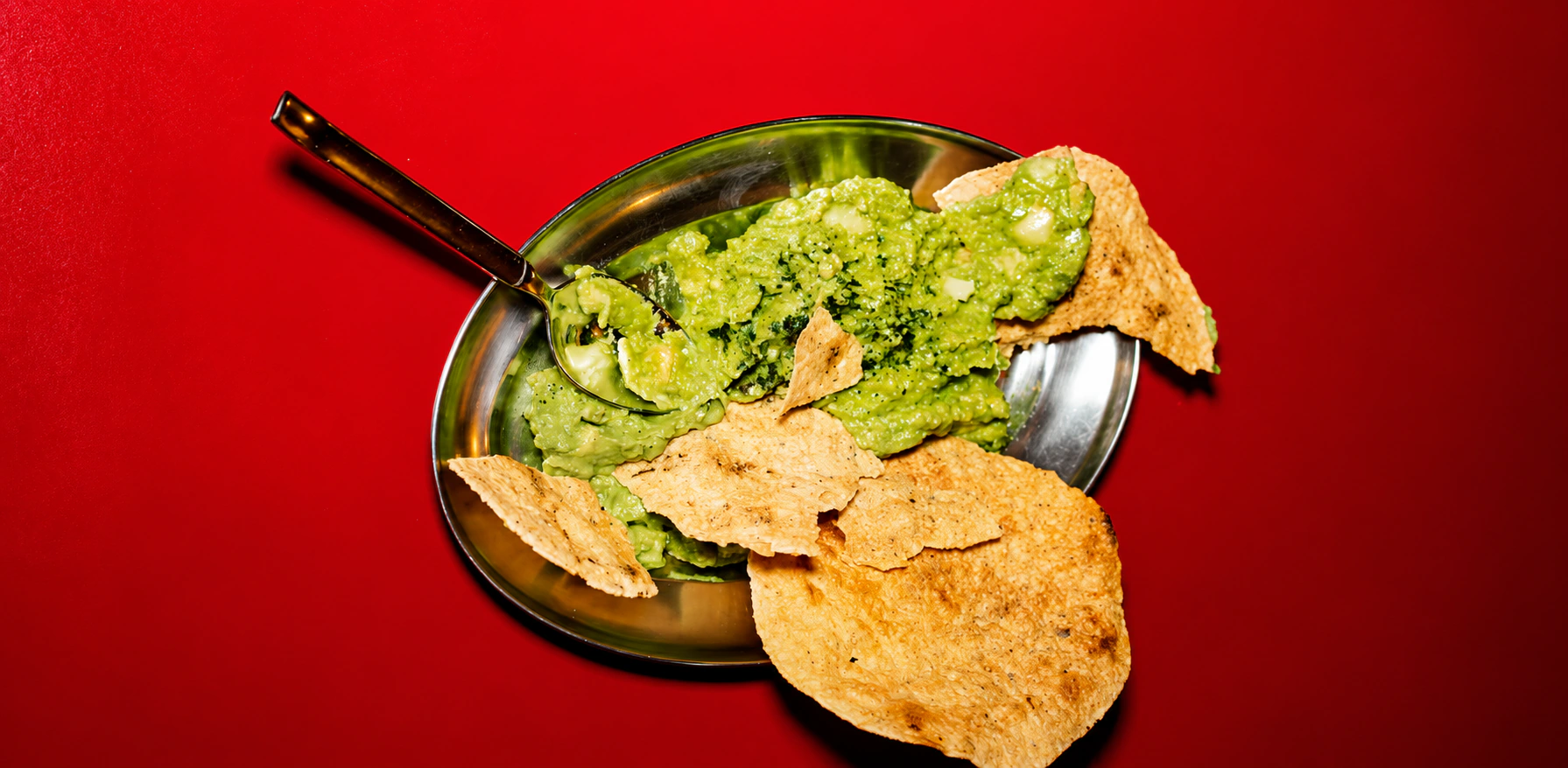 Guacamole con totopos servido en una mesa roja